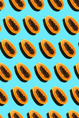 solid pattern of halves of ripe orange papayas with black seeds on a blue background