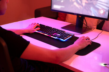 Teenage gamer, playing shooting game in his room on his personal computer all alone. Warm neon...