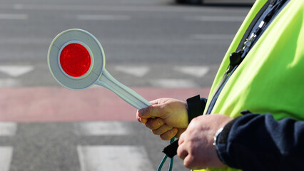  Policjant policji drogowej podczas kierowania ruchem z lizakiem do zatrzymywania pojazdów. © FotoDax