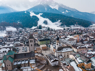 Fototapeta na wymiar High angle view of houses in village. Scenery of majestic snowcapped mountains and houses. Beautiful townscape in south tyrol during winter in europe.
