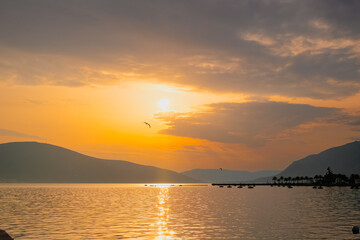 beautiful orange sunset with clouds, flying bird, mountains and reflection in the sea. relaxation and meditation paradise places of the world. beauty in nature