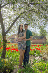 Loving couple in the garden among blooming red tulips.
