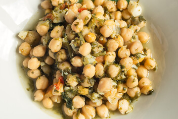 White plate with a portion of chickpea stew with spinach. Traditional recipes.