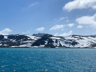 Antarctica ocean and mountain with snow, blue sky, white clouds