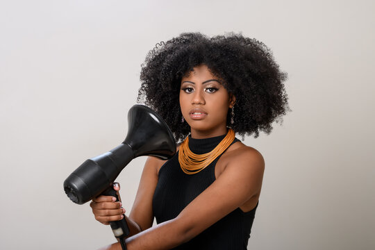 black woman using hair dryer, isolated on gray background