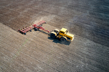 Pre-sowing processing of the field. The tractor buries the soil. Shooting from the air.