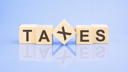 TAXES - word is written on wooden cubes on a blue background. close-up of wooden elements