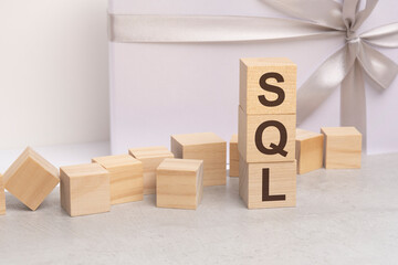 sql - letters on wooden cubes. concept on white gift box background