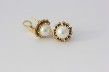 Close-up photo of white pearl earrings with diamonds in gold