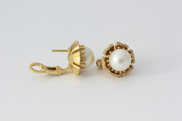 Close-up photo of white pearl earrings with diamonds in gold