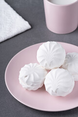 Fototapeta na wymiar White marshmallows on a pink plate on a grey table