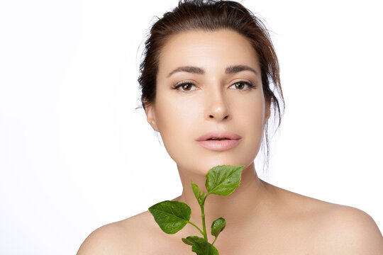 Natural beauty with green leaves. Beautiful woman with fresh hydrated and glowing skin. Bio cosmetics and skincare concept