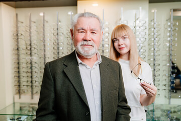 an elderly man with an ophthalmologist chooses glasses in the optics salon.