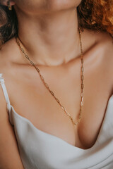 Close-up young woman wearing white sexy satin blouse and gold chain necklace. Modern fashion...