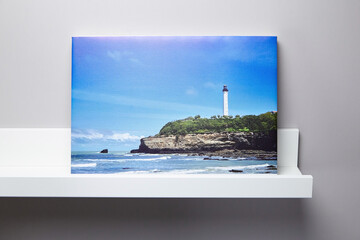 Canvas print landscape photo and white shelf hanging on grey wall