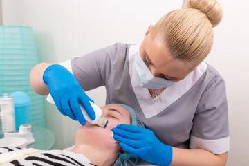 Young woman getting ultrasonic peel skin with skin scrubber.