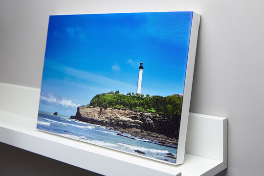 Canvas photo print with white edge and shelf hanging on grey wall