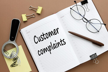 Customer Complaints. text on an open diary. stickers and magnifier