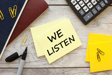 We listen. text on yellow sticky note near different stationery