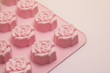Pink cookie rubber molds in the shape of roses on a pink background.