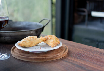 two meat or chicken patties resting on a wooden table next to the grill