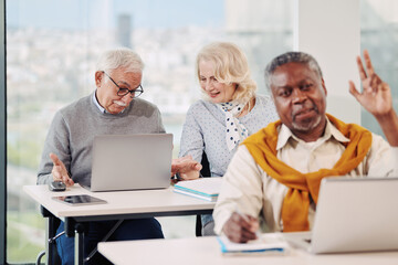A multicultural group of senior students is learning about social media on laptops in the classroom.