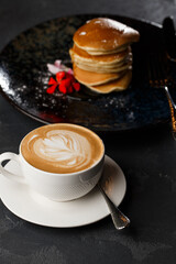 American pancakes with berries and maple syrup on black plate isolated with coffee. cafe menu