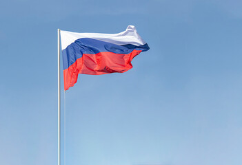 Lighting mast with Russian flag, CCTV camera and searchlights. Close-up against the clear blue sky. There is a copy space. The canvas of the flag develops smoothly in the wind.