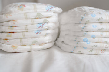 A pack of diapers on a white bed, stack of diapers