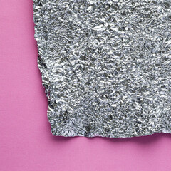 Silver crumpled aluminum tin foil on pink paper background graphic design element.