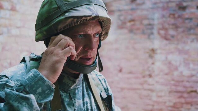 Close up military soldier with helmet and camouflage uniform using speaks on mobile phone serious. Military concept