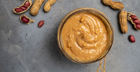 Glass jar with peanut butter or peanut paste. Long banner format. top view