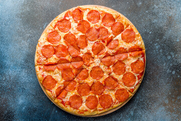 Pepperoni pizza on the board on dark blue stone table top view