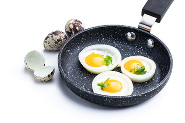 Fried quail eggs in onion ring in frying pan isolated on white