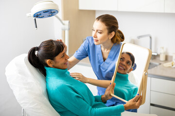Portrait of woman sitting on couch and looking at mirror during appointment with doctor at...