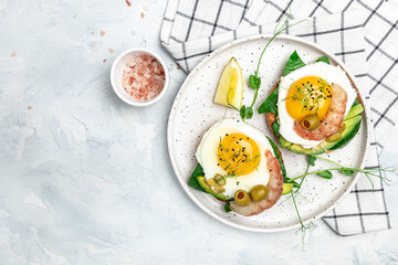 breakfast sanwich with wholemeal bread, soft fried egg, spinach, avocado, shrimps on light background, Ketogenic breakfast. superfood concept. Healthy, clean eating. Top view