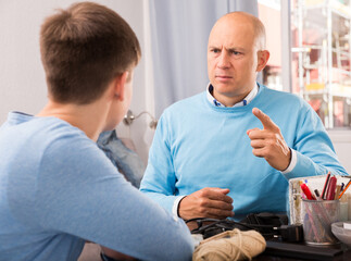 Strict father having serious conversation with teen boy at home
