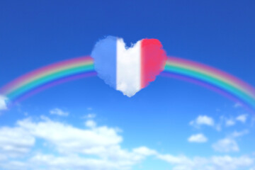 大きな虹とフランスの国旗色のハート形の雲が浮かぶ青空