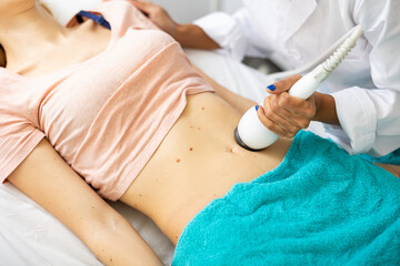 Obraz na płótnie Canvas Close up view of young woman belly during electroporation mesotherapy body treatment at aesthetic clinic