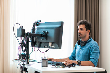 Casual man working on desktop computer in modern open plan startup office interior. Selective focus 