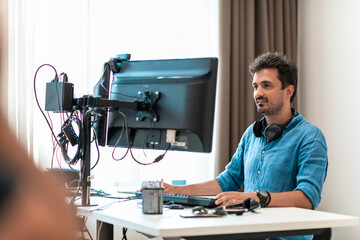 Casual man working on desktop computer in modern open plan startup office interior. Selective focus 