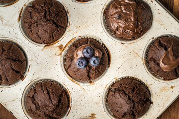 fresh baked muffins with chocolate cream and blueberries in ceramic pan top view