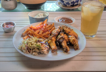 Side view of chicken wings dinner on natural white wood surface