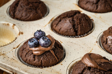 fresh baked muffins with chocolate cream and blueberries in ceramic pan