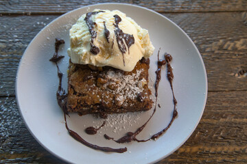 Top view of vanilla ice cream on a brownie on natural wood table