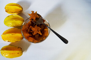 Star fruit in syrup inside a cup and four fruits on the side