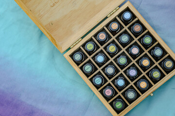 Top-down view of essential oil bottles in wooden storage box with colorful cap stickers