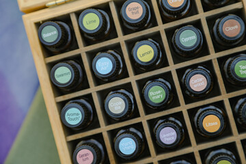 Top-down view of essential oil bottles in wooden storage box with colorful cap stickers