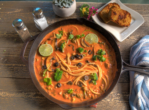 Top view of Red Thai Curry Noodle Soup on Natural Wood Table