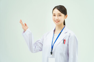 案内のポーズをする白衣の女性
